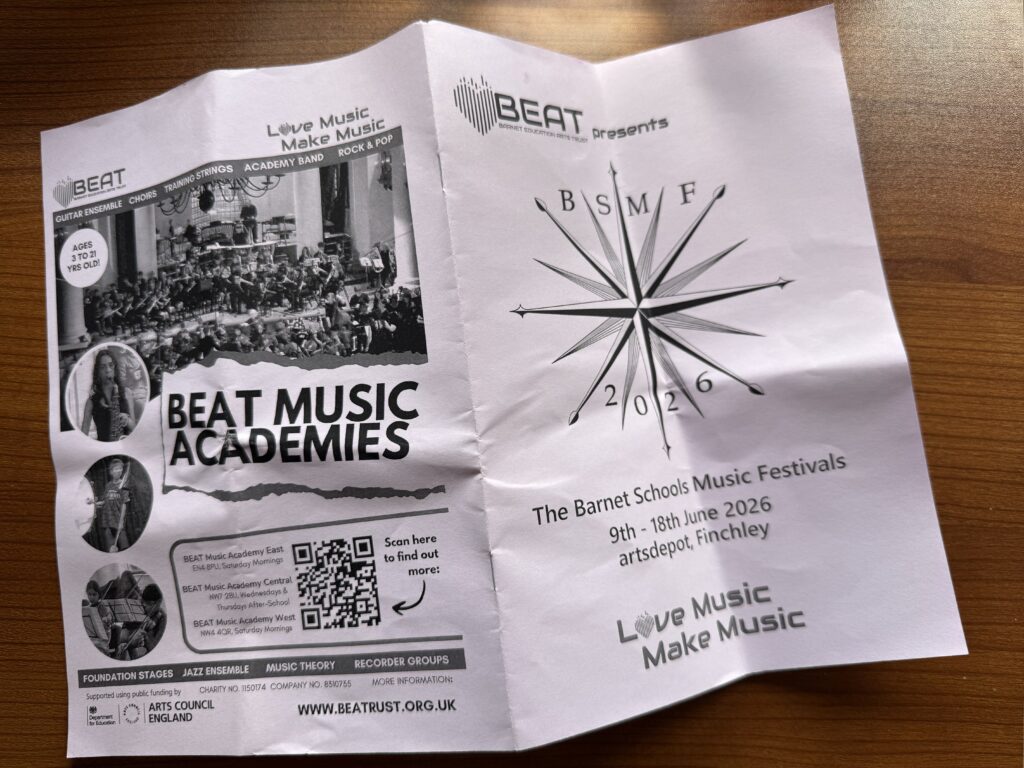 The programme for the Barnet Schools Music Festival is placed on a table. It is black text on pink paper.